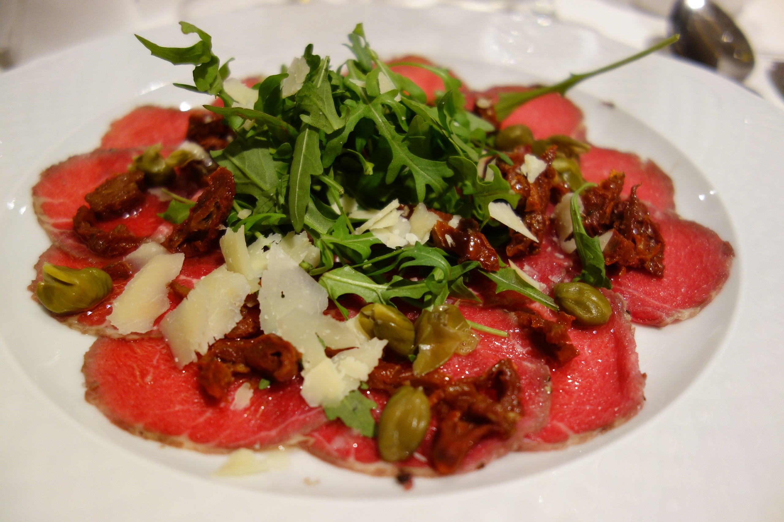 Carpaccio z sezonowej wołowiny z płatkami parmezanu, suszonym pomidorem, kaparami i listkami rucoli - restauracja Polanka